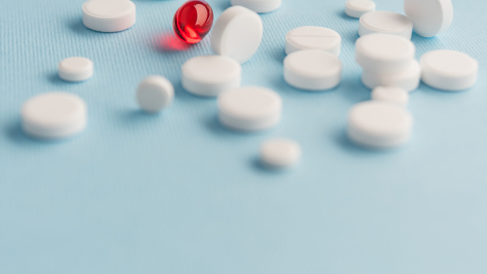 Close up of white tablets with red capsule medication
