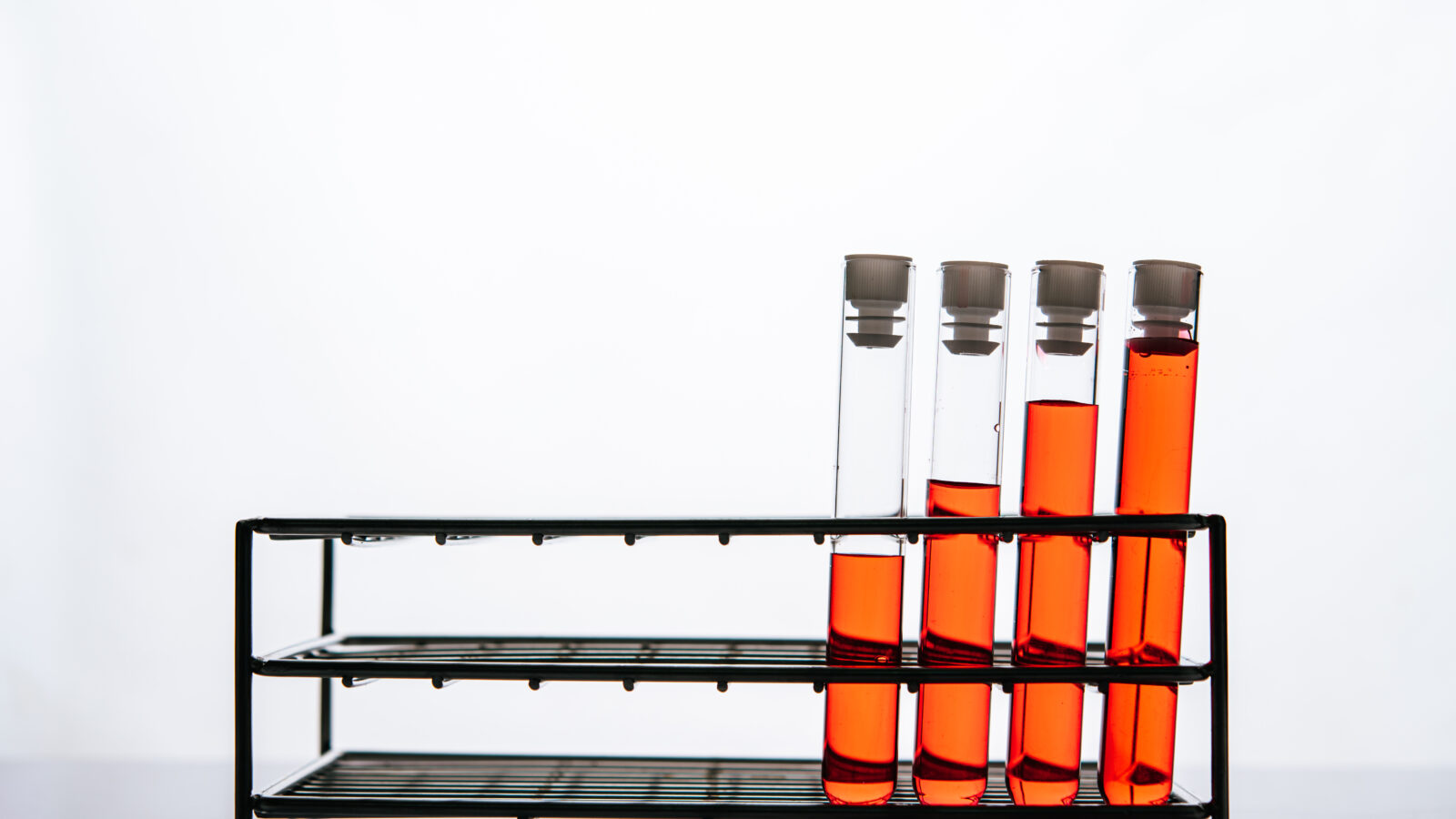 Orange chemicals in a science glass tube arranged on a shelf.